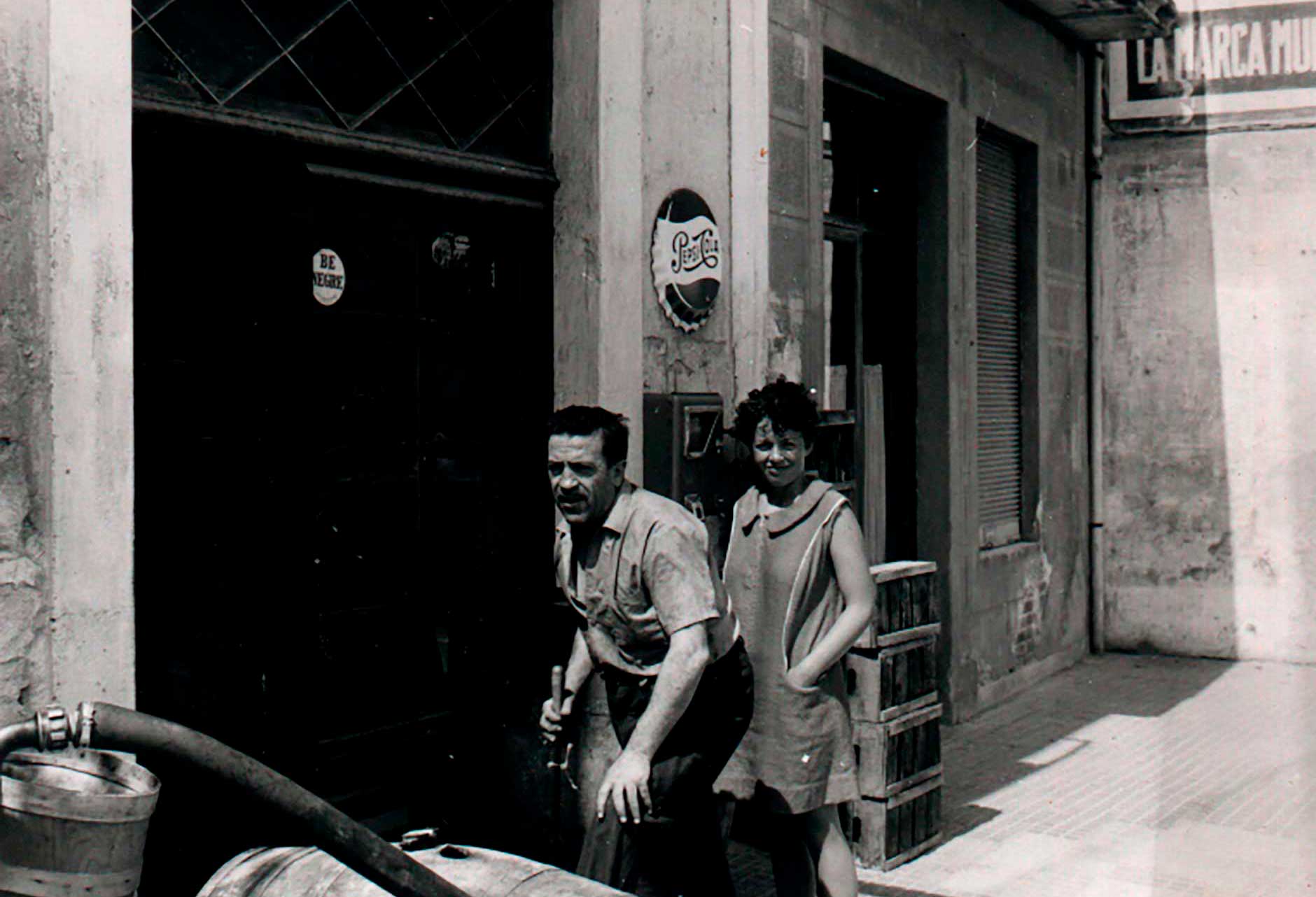 Joan Tapias Riera, 3.ª generación años 1960 con una turista observando los barriles de vino